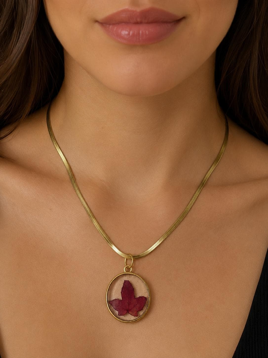 Pendente com folha bordeaux preservada em resina, aro dourado e corrente fina
